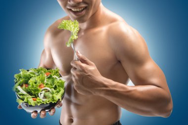 Genç mutlu kaslı adam bir salata yemek