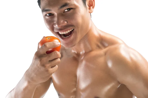 Retrato de un tipo musculoso comiendo un tomate, aislado sobre fondo blanco —  Fotos de Stock