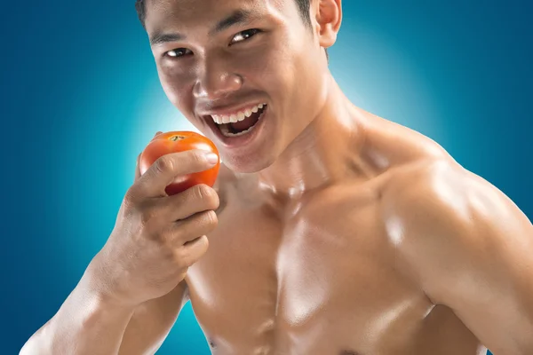 肌肉发达的家伙吃一个番茄的肖像 — 图库照片