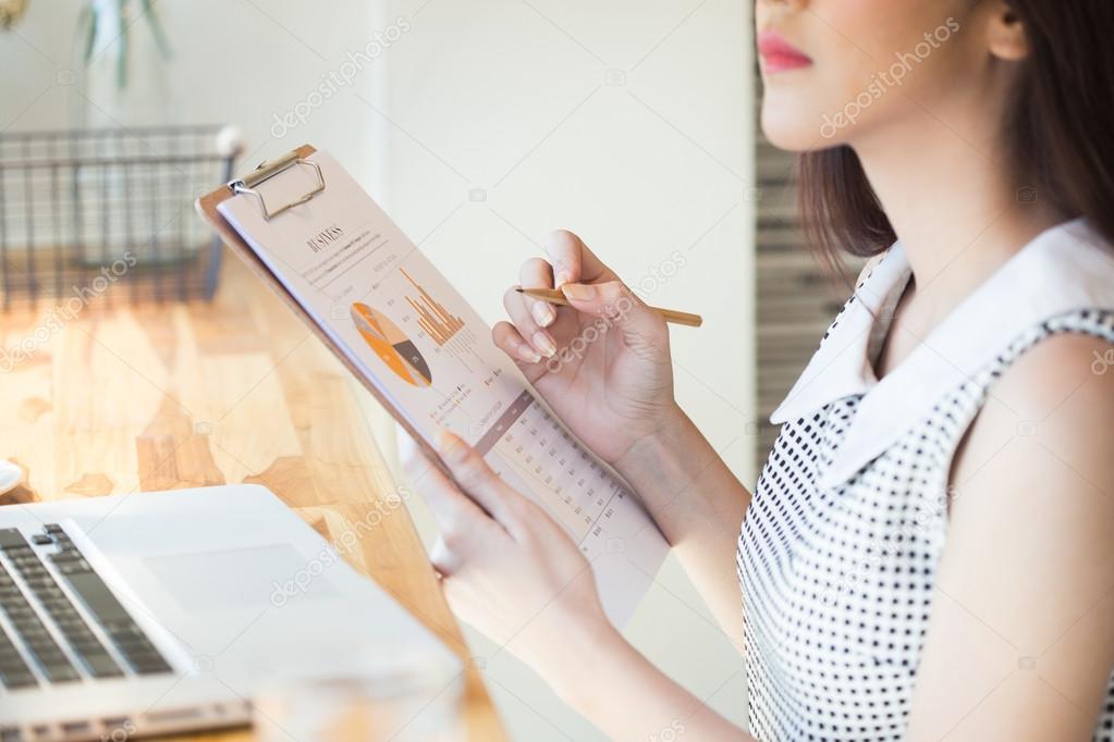 Beautiful business woman using a laptop computer and writing on 