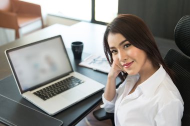 Ofiste dizüstü bilgisayar kullanan genç bir iş kadınının portresi