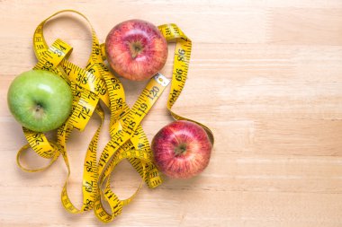 Diyet kavramı, kırmızı ve yeşil elma ve tahta üzerinde bir ölçüm bandı 