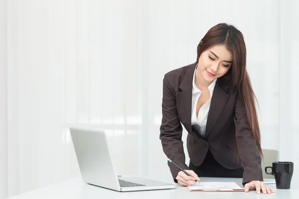 Retrato de uma jovem mulher de negócios usando laptop no escritório — Fotografia de Stock