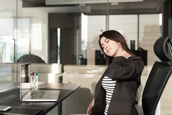 Young businesswoman with neck pain sitting at office desk — Stock Photo, Image