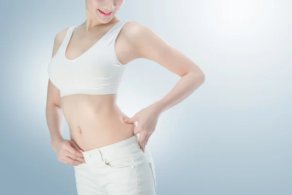 Young slim woman with little fat on her belly on background with clipping path — Stock Photo, Image