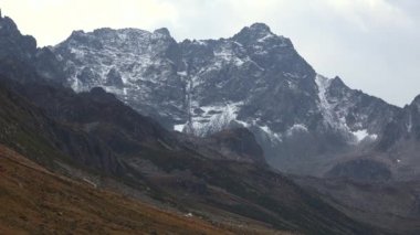 Yılın ilk karı, çayırın arkasındaki yüksek kayalık dağ zirvesine ulaşır. Long Valley 'deki karlı zirvelere doğru bakıyorum. Hilly çayırları bozkırları ovalar çayır yaylaları yaylalar dağlık yaylalar sonbahar coğrafya tablosu 4K
