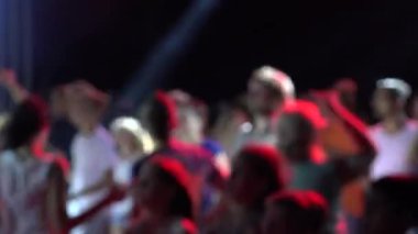 Her hıza uygun karışık müzikle dans eden insanlar. Gece kulübünde disko müzik konseri. İnsanlar dans ediyor. Genç kızlar ve oğlanlar çılgınca eğleniyorlar. Eğlence ışıklandırması efektleri gençlere konser veriyor.