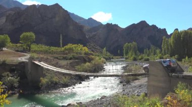 Araba tehlikeli ahşap asma köprüsünden geçiyor. Jammu ve Kashmir Nepal Himalayaları Pakistan Hindistan kuzeybatı Pamir dağları ile Hindu Kush Wakhan Koridoru Afganistan Türkiye Tibet Platosu vreal nehir yolu 4k