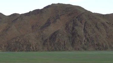 Ağaçsız Tepelerin Yanındaki Yeşil Düzlük. Kıta iklimleri genellikle sıcak ve soğuk yaz mevsimleri geçirir. Alp dağı iklimi yüksek topoğrafya bölgeleridir. Tundra flora biyolomu yere yakın cüce çalılarla karakterize edilir. Dağlık Dağ