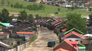 Sibirya 'da Sokakta Bir Araba Sürülüyor. Orta Asya' nın klasik şehrinde renkli çatılı evler. Geleneksel Sibirya şehirleri. Evlerin bahçeleri. Darkhan-Uul dornod Dornogovi Dundgovi Rusya Govi Altai.Caddesi Araç yolu kirli şehir 4K yolunda..