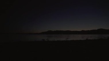 Geceleri göl coğrafyası. Hava ufukta parlıyor. Göl kıyısında gece yarısı soğuk havası. Günaydın. Karanlık, bulutsuz, sinematik arka plan manzarası. Doğanın doğal rengi.