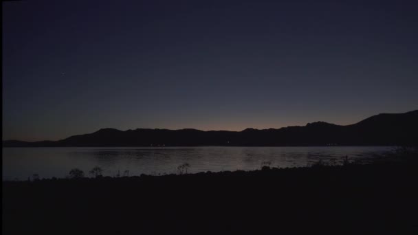 夜の湖の地形水平線に空気が明るくなっています 湖の岸に真夜中の寒さ 朝暗い黒雲のない映画的背景風景自然を見る自然の真の色シンプルな標準的な雰囲気夜明け湖畔で日の出 — ストック動画