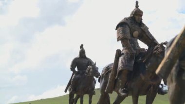 Cengiz Han 'ın atlı süvarilerinin heykelleri. Tsonjin Boldog ziyaretçi müzesi eski Xiongnu arkeolojik kültür turizm merkezi Moğol İmparatorluğu ordusu bronz metal at süvarisi süvari savaş atlısı asker 4K' ya bindi.