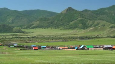 Ormanda ve nehir kıyısındaki bir Rus kasabasının renkli evleri. Dağ evi şehirlerinin evleri çitlerle çevrili ağaç koruluğu ormanları Sylvan Grove taiga çam kayısı bitkisi seyrek çayırlık çayır çayır 4K