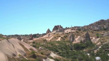 Kapadokya 'daki peri bacalarının kenarındaki Uchisar tepesi ve taş mağara mimarisi. Kireçtaşı kapüşonları ve tortulu peri bacaları kurak bir havza vadisinde kayalar. Anadolu Nevsehir muhteşem şehir merkezleri zirvesi Türkiye' nin 4K zirvesinde.