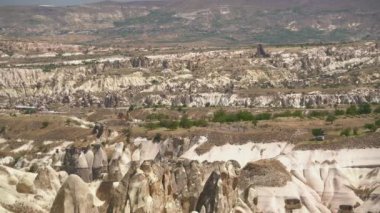 Goreme ve geleneksel mağara evleri Kapadokya 'daki peri bacalarının kenarında. Kireçtaşı başlıklar ve kurak bir havza vadisindeki tortulu peri bacası. Türkiye' nin şehir manzarası Anadolu Nevsehir Urgup Avanos Uchisar Cavusin Z12 UNESCO