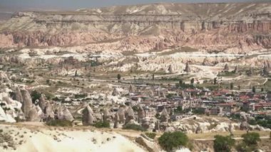 Goreme ve geleneksel mağara evleri Kapadokya 'daki peri bacalarının kenarında. Kireçtaşı başlıklar ve kurak bir havza vadisindeki tortulu peri bacası. Türkiye' nin şehir manzarası Anadolu Nevsehir Urgup Avanos Uchisar Cavusin Z12 UNESCO