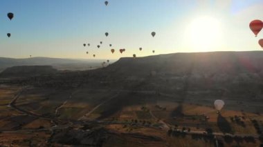 Goreme Vadisi Kapadokya 'sında uçan sıcak hava balonları ve peri bacaları. Yükselen insan taşıyan Urgup uçağı havası hasır sepet ısı enflasyonunu askıya aldı.