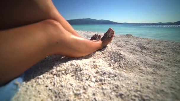 海の休日の白いビーチで太陽の下で日光浴女性の足 セクシーな女性モデル水着砂の明確な熱帯ターコイズの女の子若い足の見事な人々海岸の海辺の観光4 — ストック動画