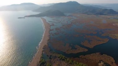 Bataklık sulak arazisi ve deniz kıyısındaki sazlık deltasının yanındaki göl. Lagoon haliçtombolo kıyı şeridi, kumsaldaki doğal bariyer, bataklık, mugla, hindi ve hava manzarası. Doğa, 4K sazlıklar.