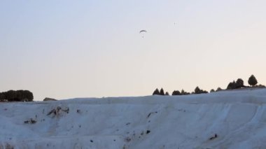 Pamukkale 'nin travertinelerinde planörlü planör, turistik doğal dünya mirası. Asma planör askıya alınmış havacılıkların üzerinden uçuyor, sabah termal şişirme, zeplin, aerostat özgürlüğü, aşırı kalsiyum, 4K