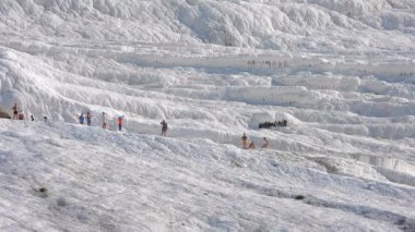 Ziyaretçiler ve turistler kalsiyum karbonat geçitlerini geziyorlar. Travertin teras oluşumları. Sıcak pınarlardan gelen sularla birikmiş edimenter kayalar. Pamukkale pamuk şatosu doğal miras alanı karbonat karbonat yüzeyi titreşiyor..