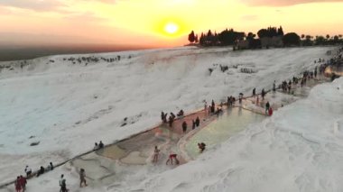 Ziyaretçiler ve turistler kalsiyum karbonat geçitlerini geziyorlar. Travertin teras oluşumları. Sıcak pınardan gelen sular tarafından birikmiş editörlük kayaları. Pamukkale pamuk kalesi doğal kireçtaşı kalesi anadolu sakinli seyahat jeolojisi 4K