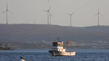 Deniz günbatımında demirli bir tekne. Körfez körfezi körfezi körfezi tekneleri küçük liman limanı ambiyansı manzarası manzaralı sinematik manzara doğa doğa görüntüsü gerçek gerçek gerçek renk, standart hindi rengi İzmir Antalya.