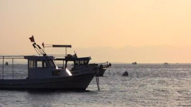 Deniz günbatımında demirli bir tekne. Körfez körfezi körfezi körfezi tekneleri küçük liman limanı ambiyansı manzarası manzaralı sinematik manzara doğa doğa görüntüsü gerçek gerçek gerçek renk, standart hindi rengi İzmir Antalya.