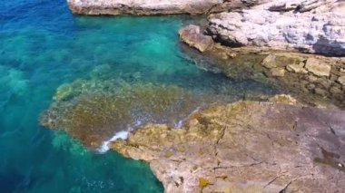 Parlak turkuaz deniz kıyısının havadan temiz resifleri. Sahil taşı kayalık kayalık, kayalık sahil kıyısı, el değmemiş deniz kıyısı. Kıyıda, şeffaf okyanus burnu. Tropikal güneş en güzel mavi kayaları aydınlatıyor..
