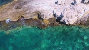 Parlak turkuaz deniz kıyısının havadan temiz resifleri. Sahil taşı kayalık kayalık, kayalık sahil kıyısı, el değmemiş deniz kıyısı. Kıyıda, şeffaf okyanus burnu. Tropikal güneş en güzel mavi kayaları aydınlatıyor..