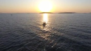 Gün batımında yelken açan balıkçı teknesi ve akşam güneşinin yansıması. Gezici tekneler sandal sandal sandal sandal çıngıraklı kayık körfez körfezi körfez körfezi, takımada, ambiyans sahnesi. Parlak, parlak, parlak, en iyi 4K parlayan manzara.