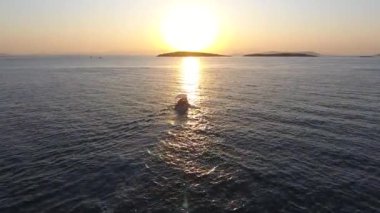 Gün batımında yelken açan balıkçı teknesi ve akşam güneşinin yansıması. Gezici tekneler sandal sandal sandal sandal çıngıraklı kayık körfez körfezi körfez körfezi, takımada, ambiyans sahnesi. Parlak, parlak, parlak, en iyi 4K parlayan manzara.