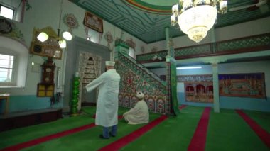 Müslüman erkekler cübbe ve türbanla küçük tarihi ahşap mescitte namaz kılıyorlar. Cami, mistik dua eden tanrı dini, gizemli dini Müslümanlık, ibadet yeri Azan salaah imam ruhani ruhu 4K