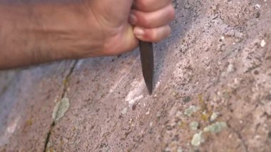 Antik insan mağara resimleri ve kaya yüzeyine demir oymacılığı ile tarihi grafiti yazıları. Taş oyma ustası, taş yontma ustası, tarih öncesi ilkel anıt menhirs obelisk megalith heykelini şekillendiren çalışmalar yapıyor..
