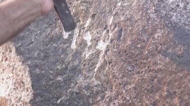 Antik insan mağara resimleri ve kaya yüzeyine demir oymacılığı ile tarihi grafiti yazıları. Taş oyma ustası, taş yontma ustası, tarih öncesi ilkel anıt menhirs obelisk megalith heykelini şekillendiren çalışmalar yapıyor..