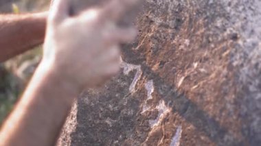 Antik insan mağara resimleri ve kaya yüzeyine demir oymacılığı ile tarihi grafiti yazıları. Taş oyma ustası, taş yontma ustası, tarih öncesi ilkel anıt menhirs obelisk megalith heykelini şekillendiren çalışmalar yapıyor..