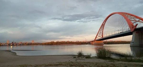 Arco vermelho da ponte suspensa sobre o largo rio Ob. Novosibirsk, Rússia. — Fotografia de Stock