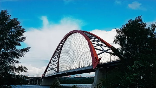 A kábeles felfüggesztő híd vörös boltozata a széles Ob folyó felett. Novoszibirszk, Oroszország. — Stock Fotó