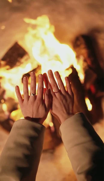 女性はたき火の近くで手を暖めている 寒い夜 ロイヤリティフリーのストック画像