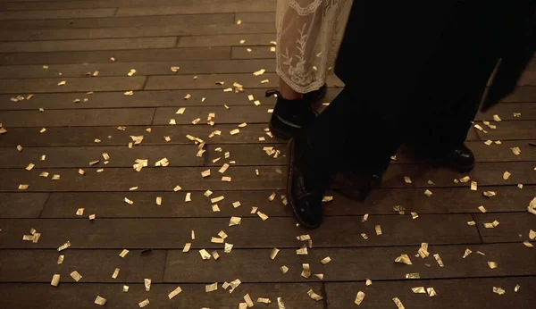 Woman feet in shoes on the floor covered in colorful confetti,Feet of couple standing on club floor with confetti