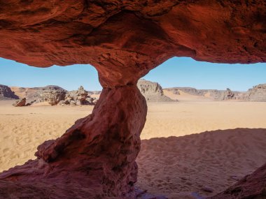 Sahra Çölü 'ndeki Kızıl Tadrart' ın kaya oluşumları ve altın tepecikleri. Berrak bir gökyüzünün altında çarpıcı bir doğal manzara. Sahra Çölü, Cezayir 'de gün doğumunda kum tepeleri ve kaya oluşumlarıyla Kızıl Tadrart' ın manzarası.