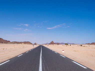 Kızıl Tadrart 'ın çöl manzarası. Mavi gökyüzünün altında kaya oluşumları ve altın kum. Cezayir Sahra 'sının doğal manzarası.