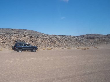 Kızıl Tadrart 'ın çöl manzarası. Mavi gökyüzünün altında kaya oluşumları ve altın kum. Cezayir Sahra 'sının doğal manzarası.