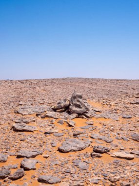 Kızıl Tadrart 'ın çöl manzarası. Mavi gökyüzünün altında kaya oluşumları ve altın kum. Cezayir Sahra 'sının doğal manzarası.