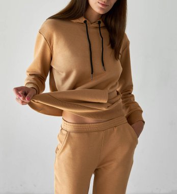 Uzun kollu kapüşonlu, bej bej bir kostüm.