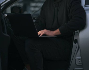 Girişimci arabada dizüstü bilgisayar kullanıyor. Yüzü olmayan basit bir fotoğraf.