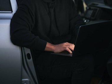 Girişimci arabada dizüstü bilgisayar kullanıyor. Yüzü olmayan basit bir fotoğraf.