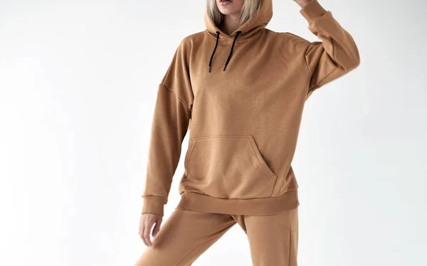 girl wears light brown hoodie and pants. isolated photo of women wearing nude color fleece textile outfit.