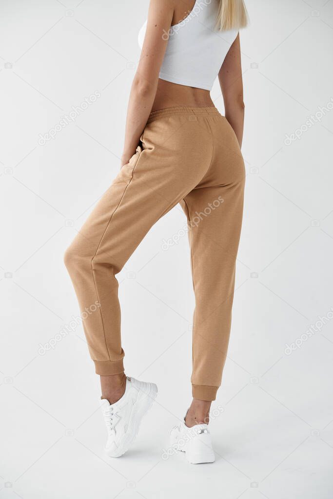 woman wears khaki pants. fit girl is standing in beige joggers